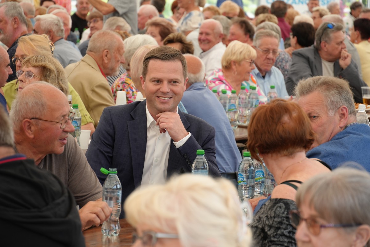 Starosta siedzacy przy stoliku z grupą seniorów.