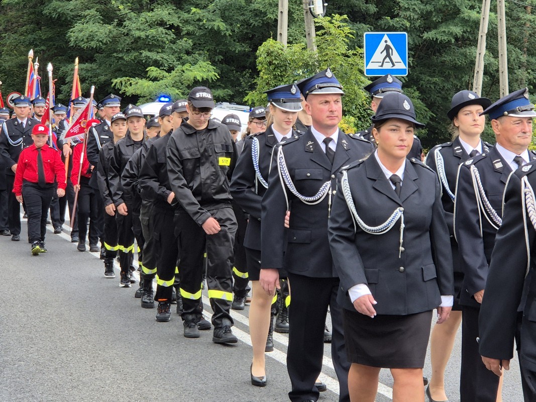 Strażacy idą drogą z kościoła w stronę remizy