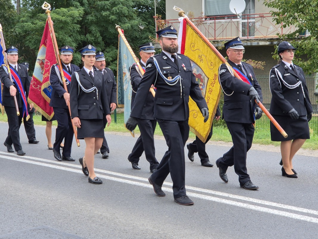 Strażacy idą drogą z kościoła w stronę remizy