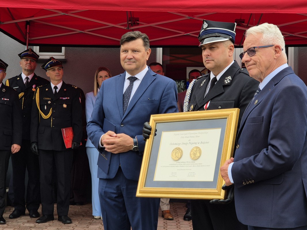 Goście wręczają pamiątkowe tablice. Na zdjęciu trzej mężczyźni