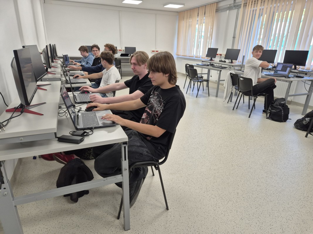 Uczniowie siedza przy komputerach w pracowni informatycznej