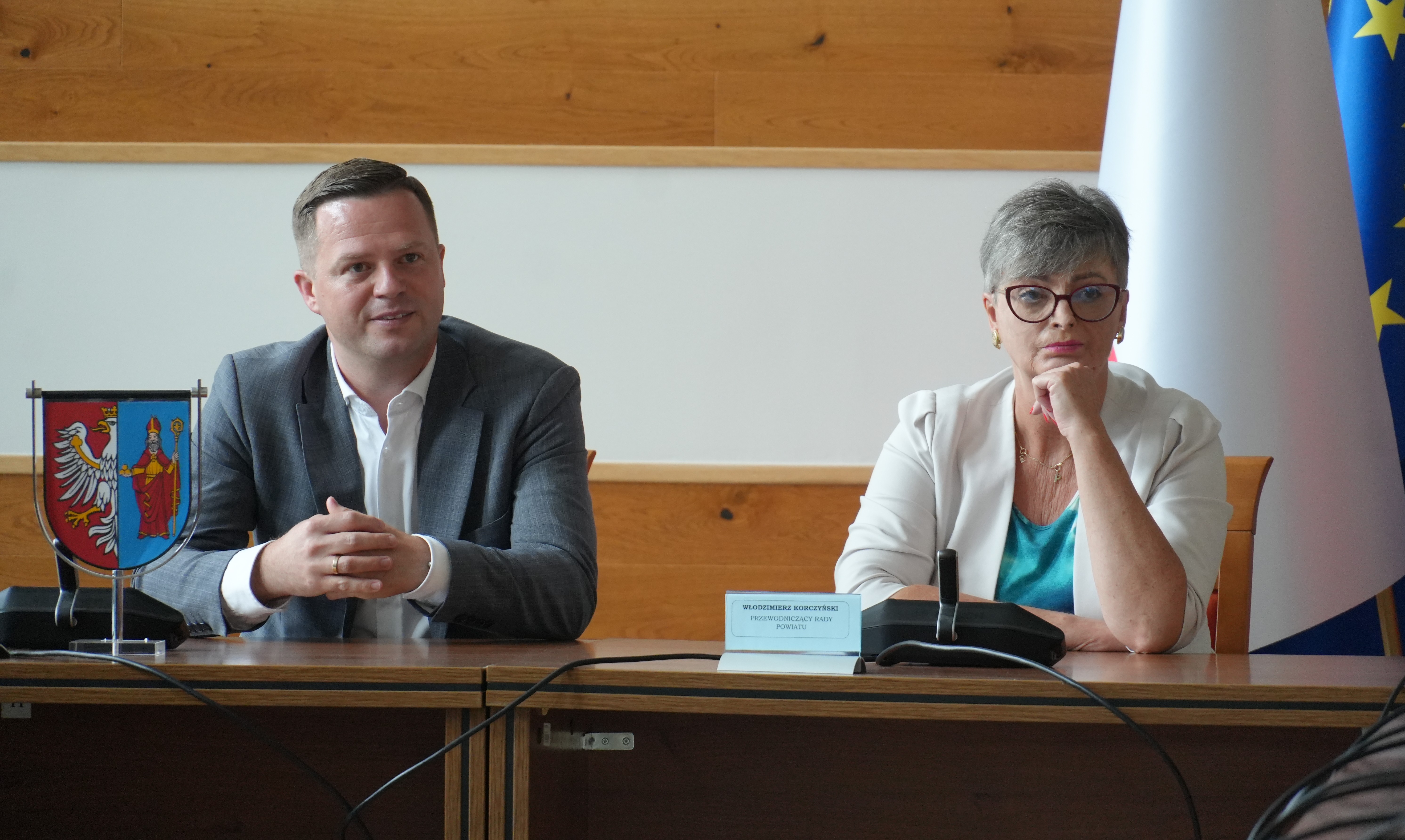 Starosta Bartłomiej Gębala i wicestarosta Ewa Jędrysik siedzą przy stole i słuchają zgromadzonych