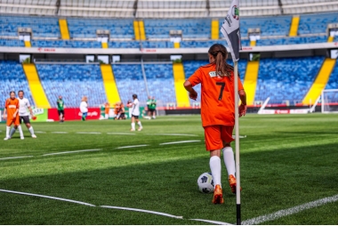 Zdjęcie kilunastu dziewcząt grających w piłke nożną na stadionie. 