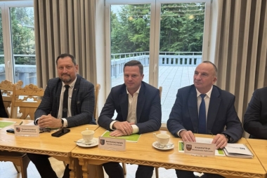 Mężczyźni w garniturach siedzą przy drewnianych stołach