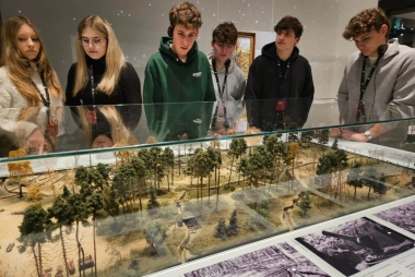 Młodzież nachylona nad makietą w muzeum 