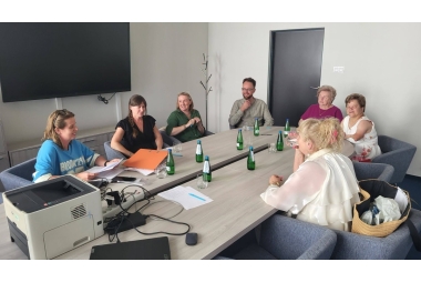 Zdjęcie kilku osób siedzących przy stole w sali