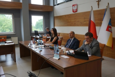 Pezydium rady: przy biurku kobieta i dwóch mężczyzn 