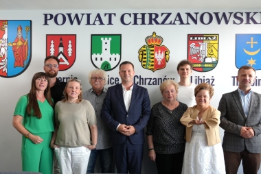 Członkowie rady stoją na tle ściany z napisem Powiat Chrzanowski oraz herbami gmin