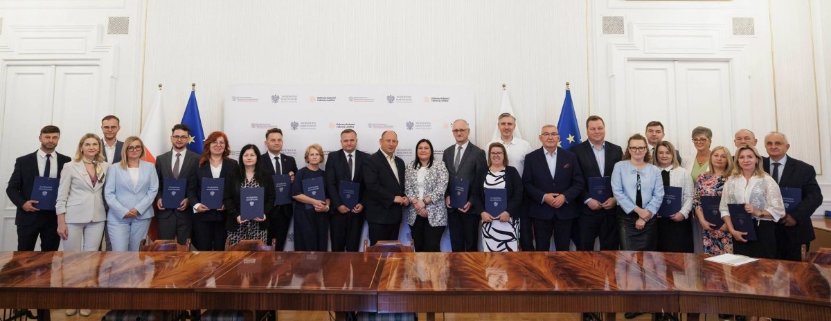 Kobiety i mężczyźni pozują do zdjęcia w urzędzie wojewódzkim w Krakowie